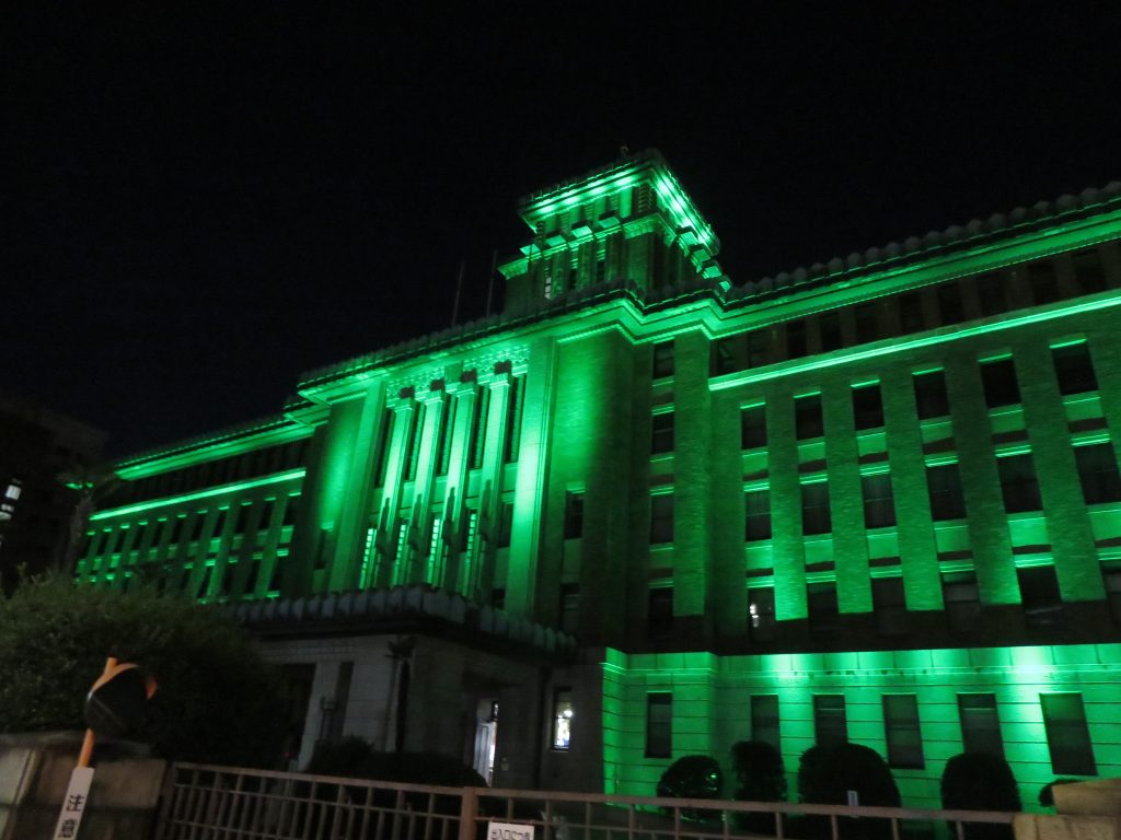 A stone building of the Kanagawa Prefectural Office in Japan illuminated in green.