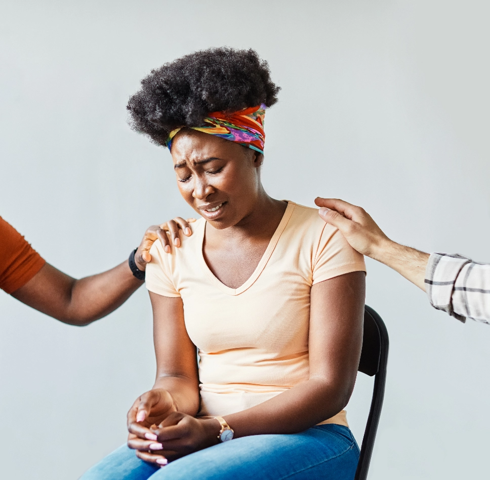 A crying woman being comforted by people.